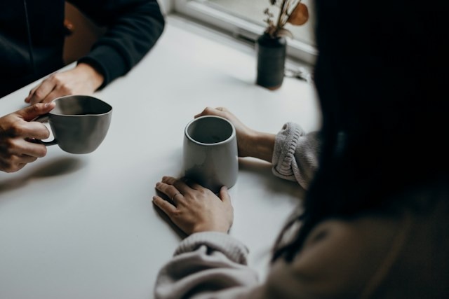 Deux personnes en conversation détendue autour d'un café, illustration de la vente par la relation